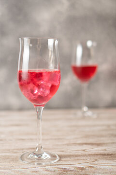 Two glasses of rose cocktails. Sparkling red cocktail with ice made at home. Vertical image. Homemade red cocktails