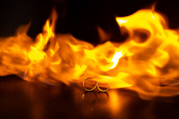 Wedding rings on fire with reflection on black.selective focus. A stream of fire.