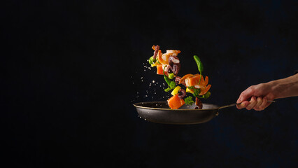 Beautiful still life. Assorted seafood - pieces of red fish, octopus, shrimp in a pan in a frozen flight on a black background. Healthy seafood, gourmet food. Restaurant menu.