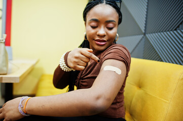Stay safe! Black woman showing vaccinated arm after vaccine injection.