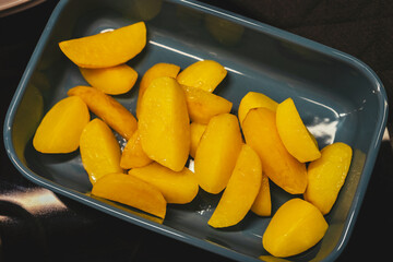 Baked potato slices, wedges in a blue ceramic bowl.