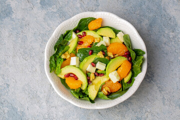 Close up view of spinach, avocado salad with orange, pomegranate and walnut