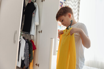 Preteen boy getting ready for school. Cute little boy open the closet wardrobe and select clothes...