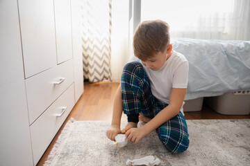 Preteen boy in pajamas putting on socks, morning routine, preparation. Tween boy wearing his socks to get ready for school. - Powered by Adobe
