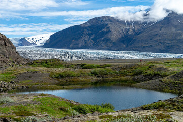 Glacier with lake in the front and mountains in the background