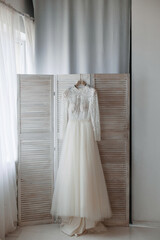The wedding dress hangs on the dressing room.
