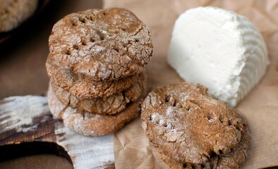 bread cakes on a yeast-free dough, stacked on a wooden board, next to them lies a piece of homemade goat's milk cheese. The concept of cooking at home, baking homemade bread. close-up