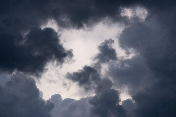 Hanging dark lead and heavy clouds against the background of an almost white sunset sky