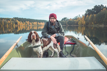 A bearded man traveling with a Springer spaniel on a boat.