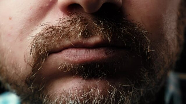 The man is eating a slice of pizza. Close-up. A man with a mustache and a beard is chewing.
