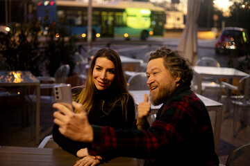 couple on a terrace in the evening taking a selfie