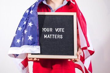 kid boy with american flag holding letter board with text Your Vote Matters on white background