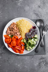 Food dieting concept, tuna salad. Couscous salad with conserved tuna, tomatoes, cucumbers and purple onions on table. Copy space.