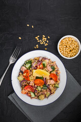 Food dieting concept, tuna salad. Couscous salad with conserved tuna, tomatoes, cucumbers and purple onions on table. Copy space.