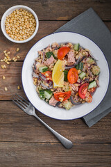 Food dieting concept, tuna salad. Couscous salad with conserved tuna, tomatoes, cucumbers and purple onions on table. Copy space.