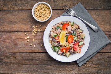 Food dieting concept, tuna salad. Couscous salad with conserved tuna, tomatoes, cucumbers and purple onions on table. Copy space.