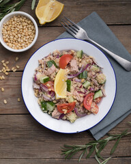 Food dieting concept, tuna salad. Couscous salad with conserved tuna, tomatoes, cucumbers and purple onions on table. Copy space.
