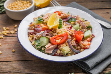 Food dieting concept, tuna salad. Couscous salad with conserved tuna, tomatoes, cucumbers and purple onions on table. Copy space.
