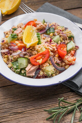 Food dieting concept, tuna salad. Couscous salad with conserved tuna, tomatoes, cucumbers and purple onions on table. Copy space.