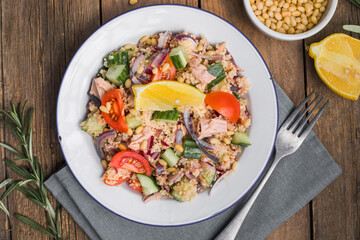 Food dieting concept, tuna salad. Couscous salad with conserved tuna, tomatoes, cucumbers and purple onions on table. Copy space.