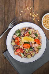 Food dieting concept, tuna salad. Couscous salad with conserved tuna, tomatoes, cucumbers and purple onions on table. Copy space.
