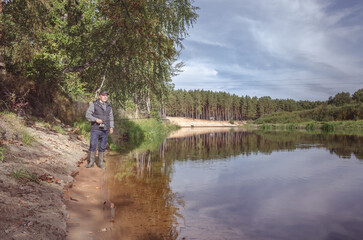 Fototapeta na wymiar Fisherman on the bank of a beautiful river.