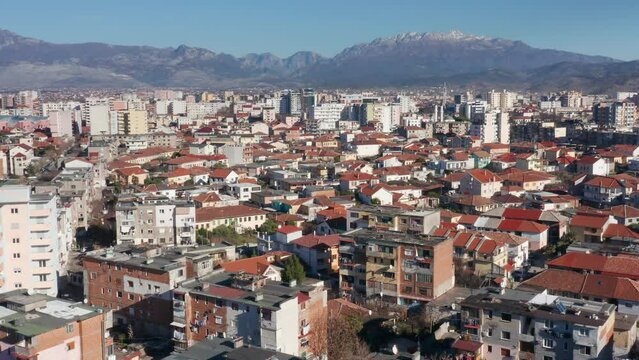 Shkoder Albania cityscape - skyline of a city, with buildings and houses, surrounded by high hills and mountains. Aerial drone view of Shkodra (Skadar) on a sunny day with clear blue sky.
