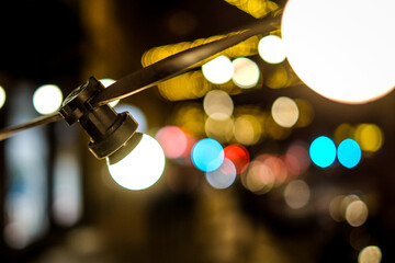 Outdoor string lights hanging on a line on street at night. Beautiful bokeh lights. Selective focus