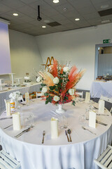 Big floral wedding centrepiece, made out of white roses and pampas grass on a white table in a reception venue.