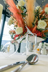 Big floral wedding centrepiece, made out of white roses and pampas grass on a white table in a reception venue.