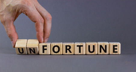 Fortune or unfortune symbol. Businessman turns wooden cubes and changes the concept word unfortune to fortune. Beautiful grey table, grey background copy space. Business, fortune or unfortune concept.