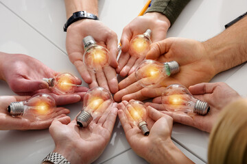 Teamwork and brainstorming concept with businessmen that share an idea with a lamp - obrazy, fototapety, plakaty