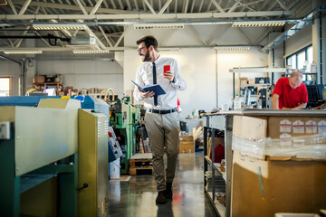 Obraz premium A happy supervisor walking around printing shop and monitoring works.