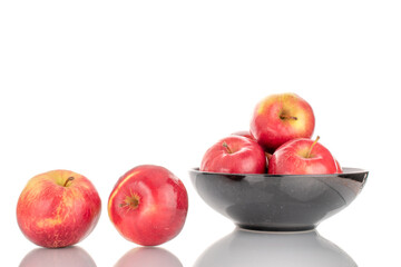 A few sweet organic, red apples with a black ceramic plate, macro, isolated on a white background.

