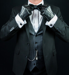 Portrait of Gentleman in Dark Formal Attire and Leather Gloves Straightening Bow Tie. Vintage Style...