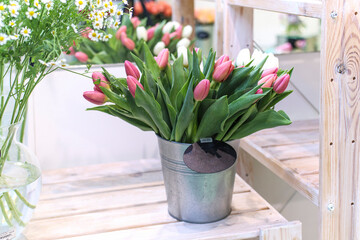 Bouquets of white and red tulips and daisies in a steel bucket for sale in a flower shop.