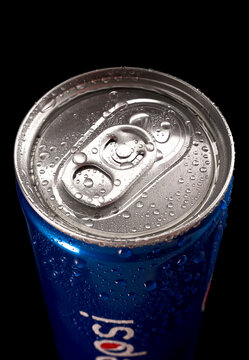 On the black background a narrow 250ml can of Pepsi with water drops. Top view.