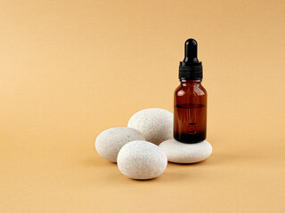 Cosmetic mean for facial care. Pipette bottle on stone filled with essential oil, essence, serum...
