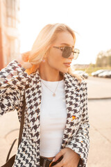 Beautiful young girl blonde with glasses in fashionable casual clothes with a stylish coat, white...