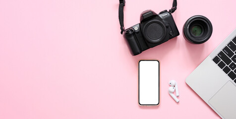 Camera, lens, laptop and smartphone with blank white display on pink background. Photographer's workplace. Flat lay, copy space.