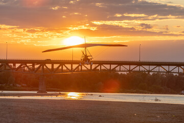 A motor glider at sunset over the bridge
