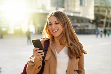 Surprised student girl watching excited her smartphone in city street