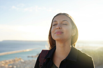 Beautiful young woman with closed eyes breathing relaxing enjoying sun at sunset. Beauty sunshine...