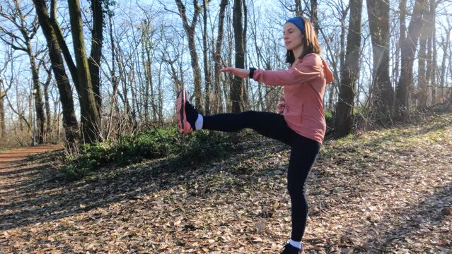 Fitness young woman doing workout in forest. Warming up exercise. Sunny first day of spring in nature. Sports girl practicing outdoor. Slow motion.