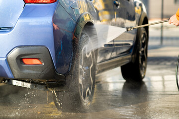 Closeup of male driver washing his car with contactless high pressure water jet in self service car wash