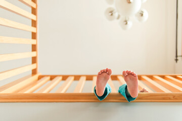 A child dangles their feet from a second level balcony