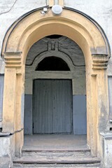 one gray wooden door on a brown concrete wall of a historic building