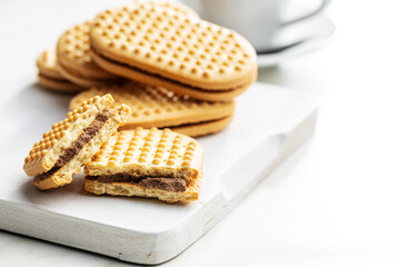 Sweet sandvich cookies. Biscuits with cocoa cream filling on white cutting board.