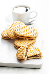 Sweet sandvich cookies. Biscuits with cocoa cream filling on white cutting board.