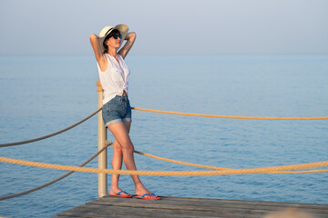 Young woman in casual outfit relaxing on seaside on warm summer day